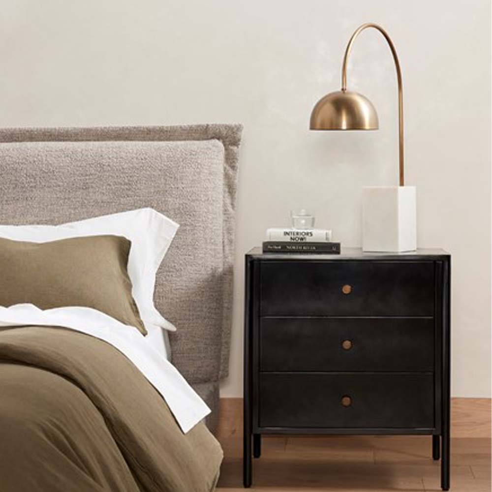 Bedroom with upholstered headboard and Black three drawer 'Soto' nightstand by four hands furniture