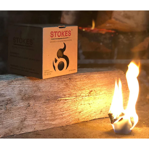 Brown box of Stokes natural fire starters on a log with a lit fire starter