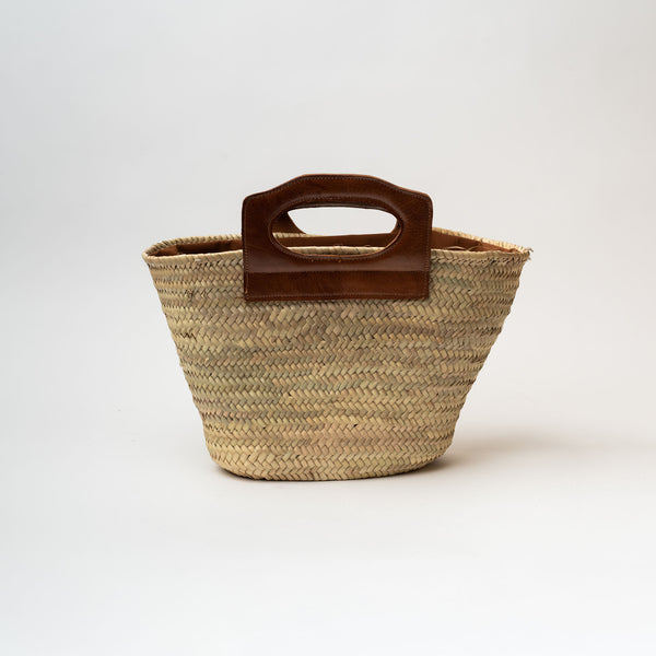 Straw oval bag with leather cut out handle on a white background