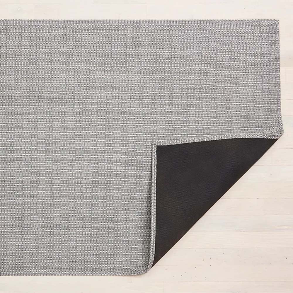 Chilewich thatch woven floor mat in dove on a light wood floor