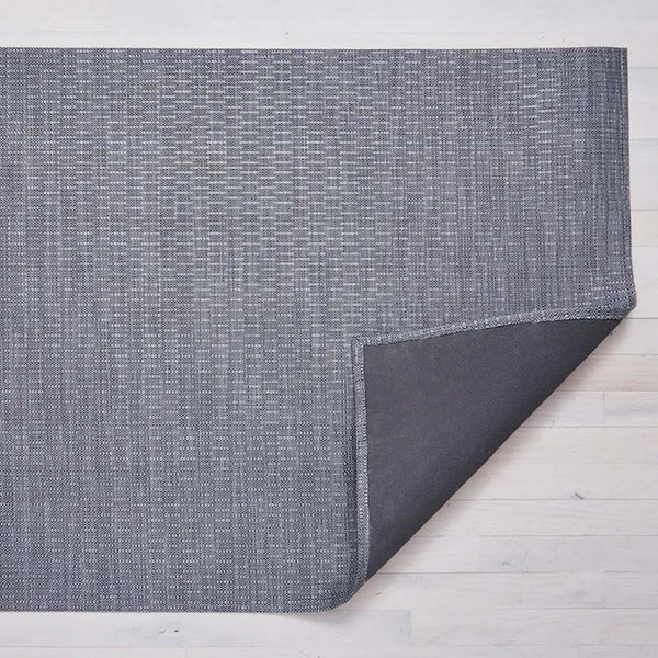 Chilewich thatch woven floor mat in pewter grey on a light wood floor