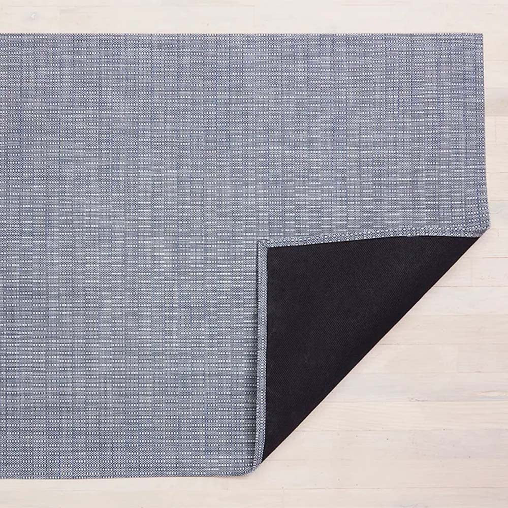 Chilewich thatch woven floor mat in blue 'rain' color on a light wood floor