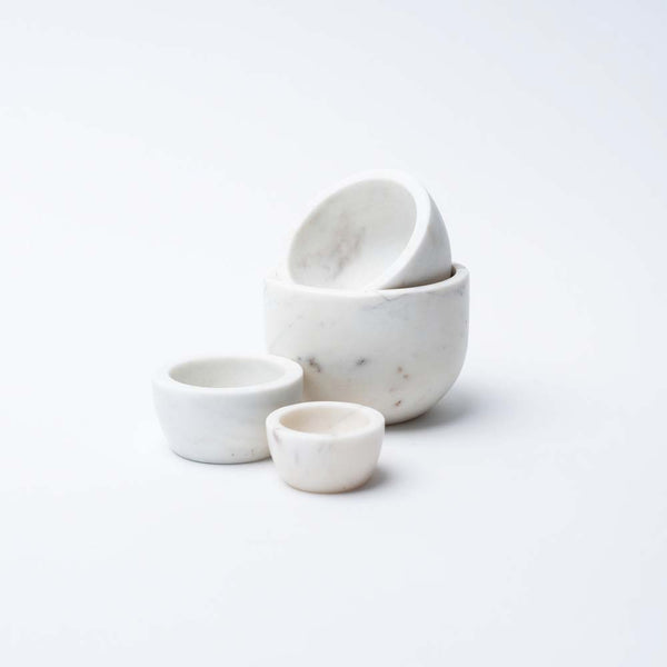 Set of four White marble nesting bowls for measuring on a white background