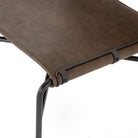 Close up of leather seat on Four hands brand wharton chair with black iron frame and dark brown leather seat on a white background