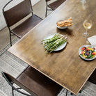 Dining room table viewed from above with geometric white patterned rug and Four hands brand wharton chair with black iron frame and dark brown leather seats