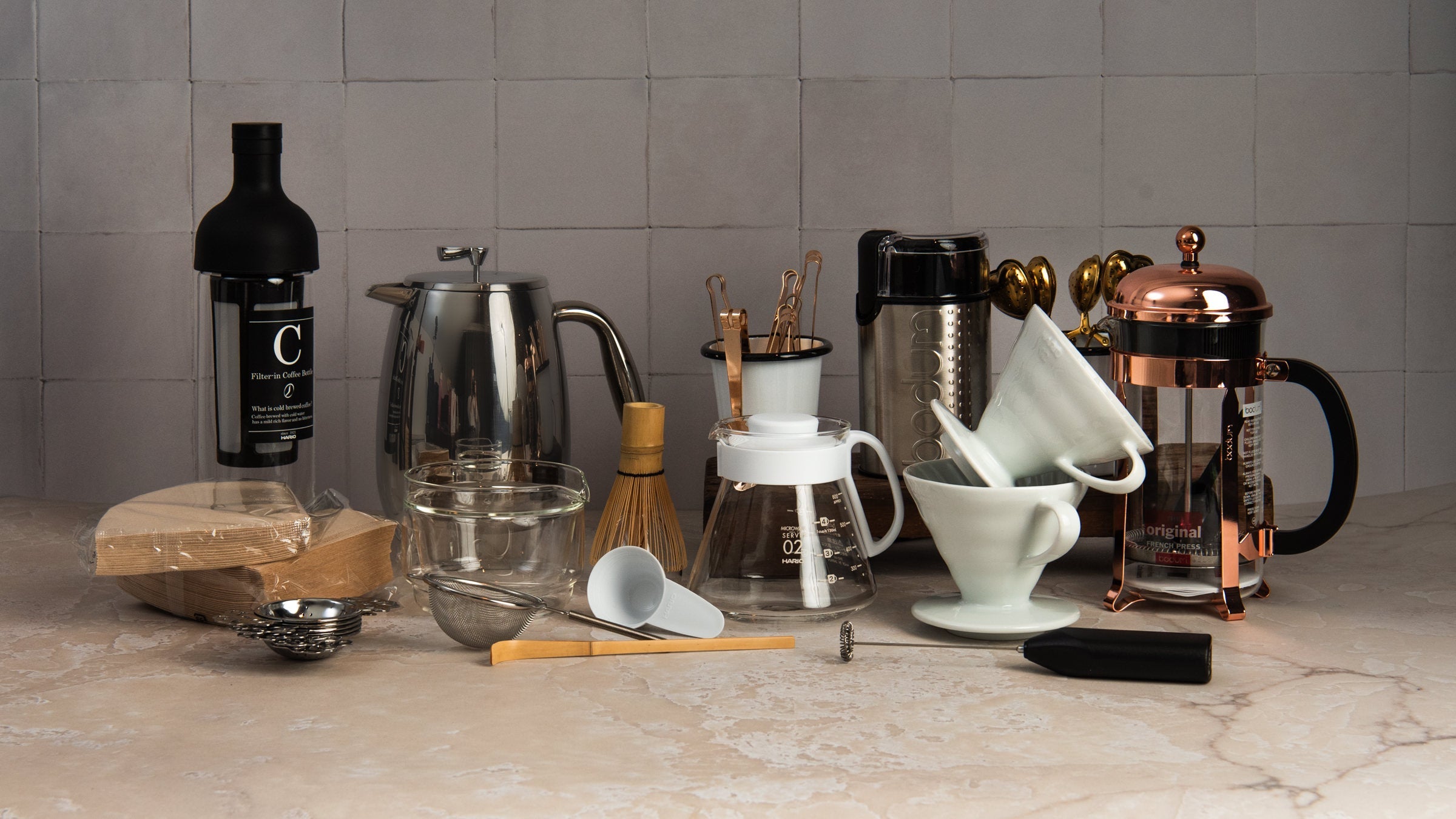 Collection of coffee makers, pour over drippers and matcha tea making tools on a kitchen counter at Addison West