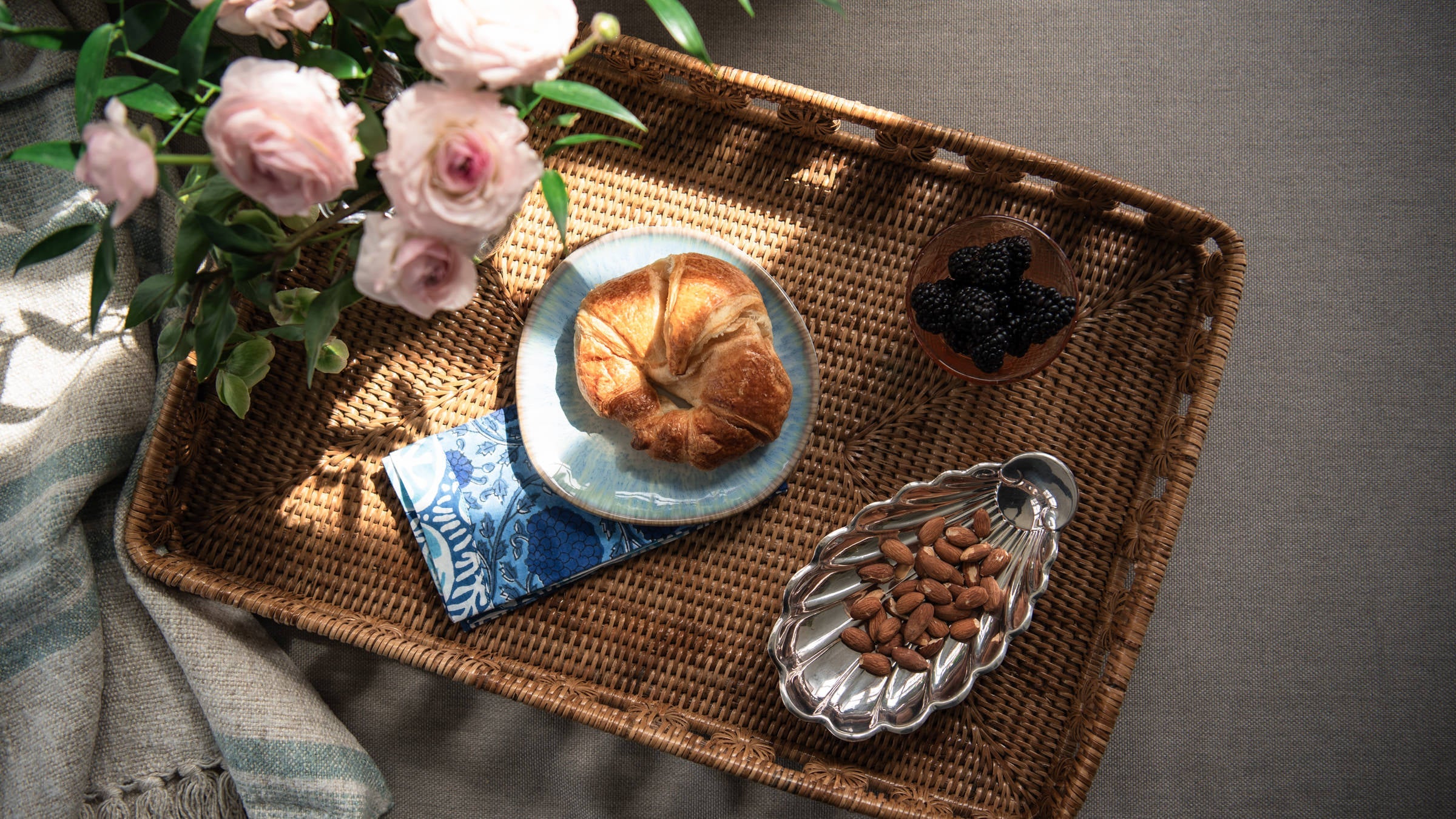 Rattan tray from above with plates and food and flowers in a vase at Addison West