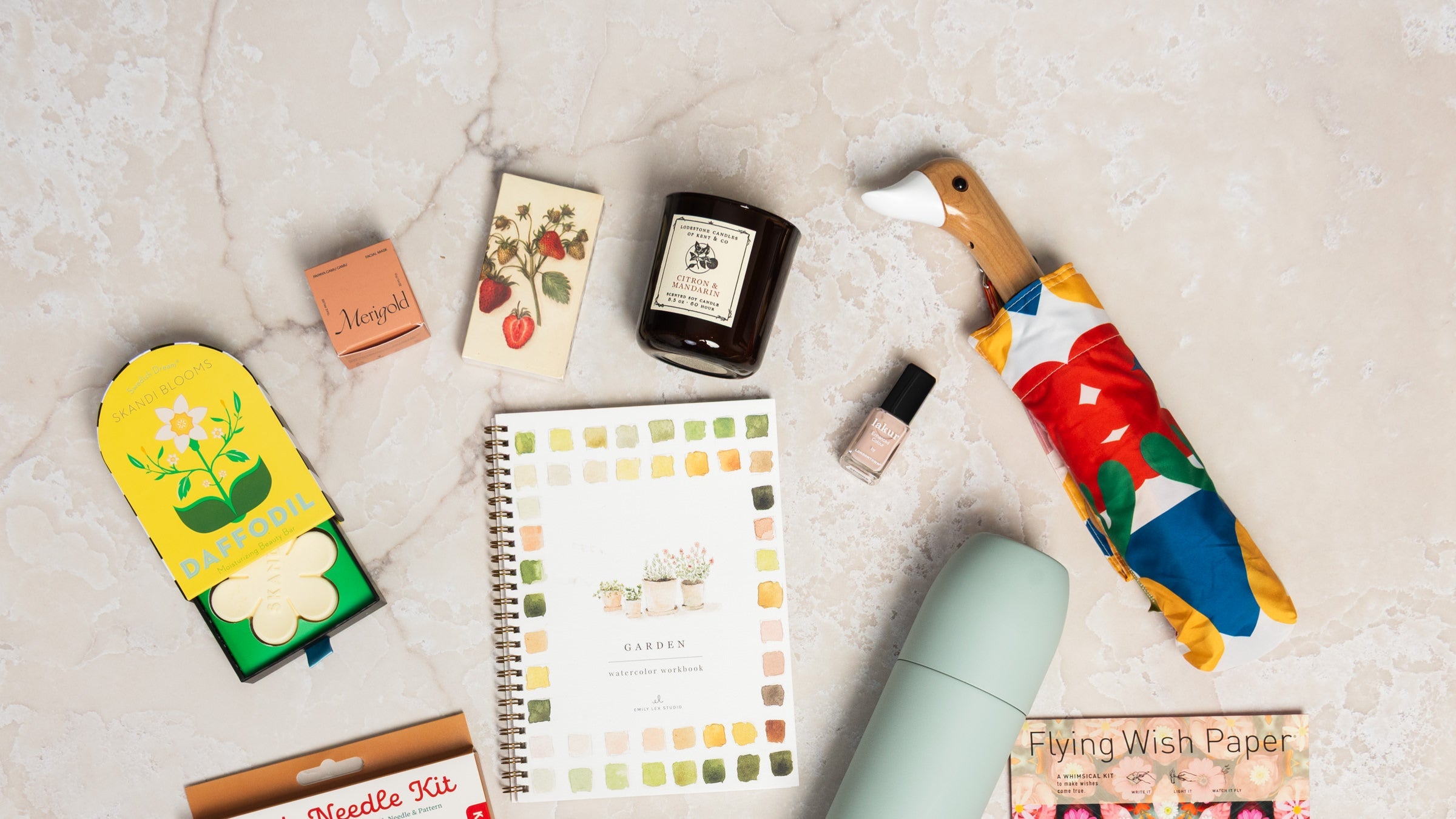 Gifts for her including picture frames, socks, watercolor workbook, books, candles, mugs and a sweater on a table at Addison West.