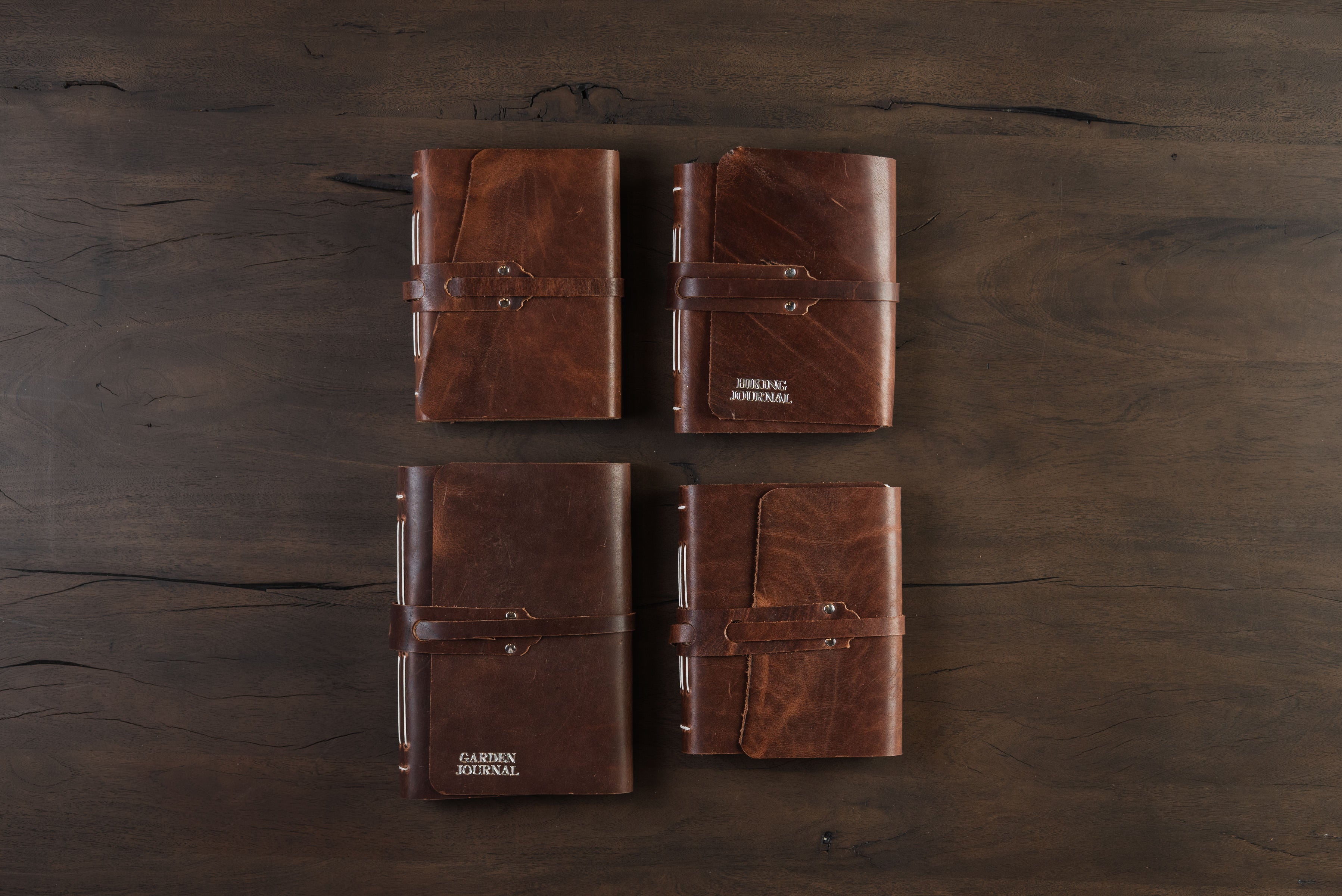 Collection of hand-bound leather journals made in Vermont on a dark wood table at Addison West