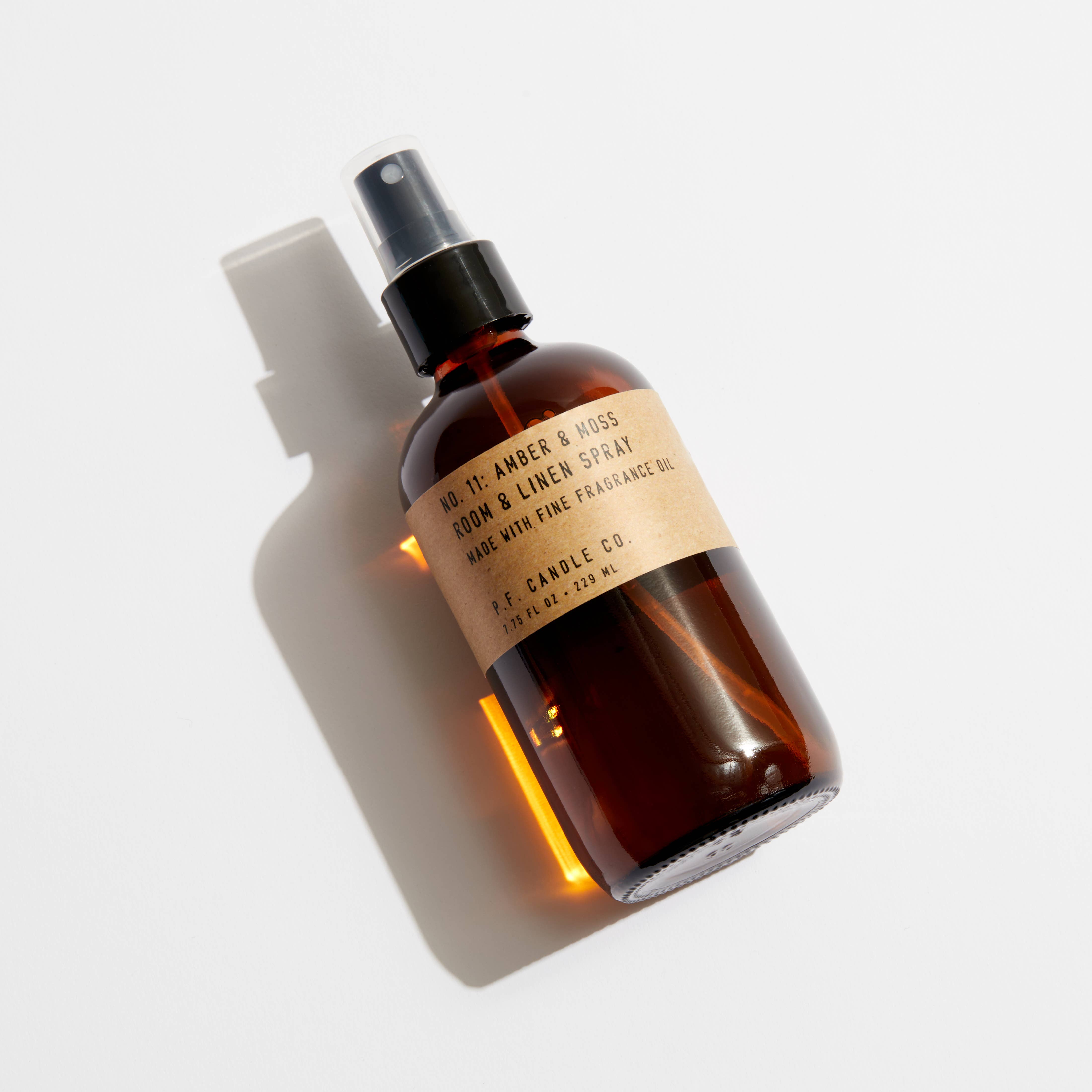 Brown PF Candle Amber and Moss Linen spray bottle with a label on a light gray background