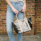Extra Small Uashmama Giulia Carryall Tote Bag in Peltro carried by a model in front of a brick wall at Addison West