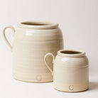 Two ceramic jars, one larger and one smaller, on a light background