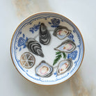 Decorative ceramic plate with oyster shells and lemon slices on a marble surface