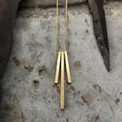 Tiny Anvil Brass Tri Pillar Necklace on a grey background at Addison West