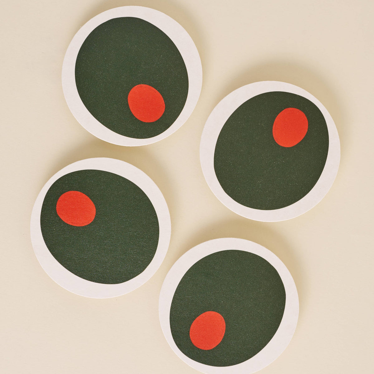 Four round coasters with olives on a beige background