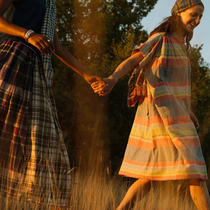 Two people holding hands in a field with plaid clothing.