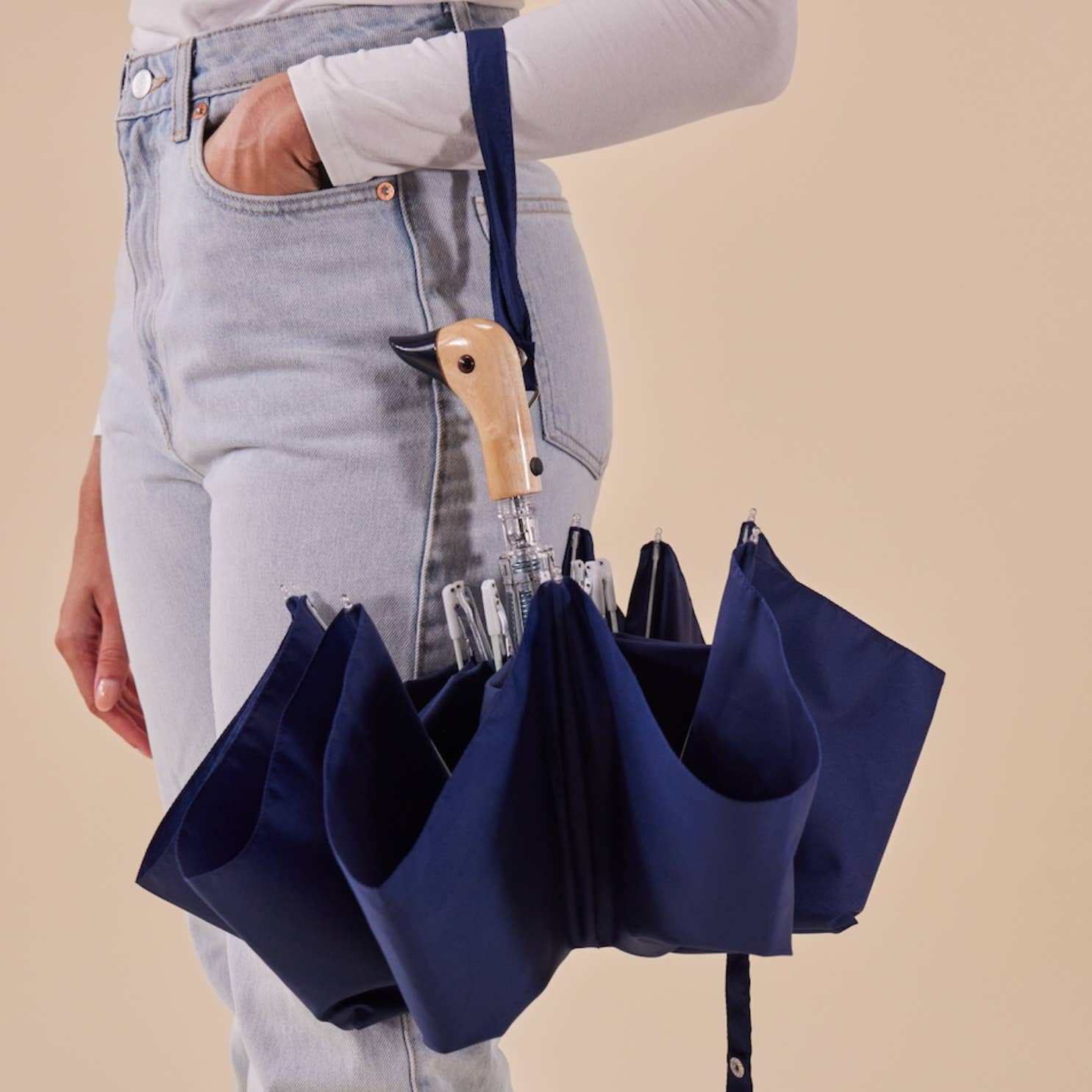 Person holding Original Duckhead Navy Eco-Friendly Umbrella on a beige background at Addison West