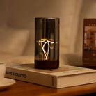 Decorative lamp on a book with a cup and a plant in the background