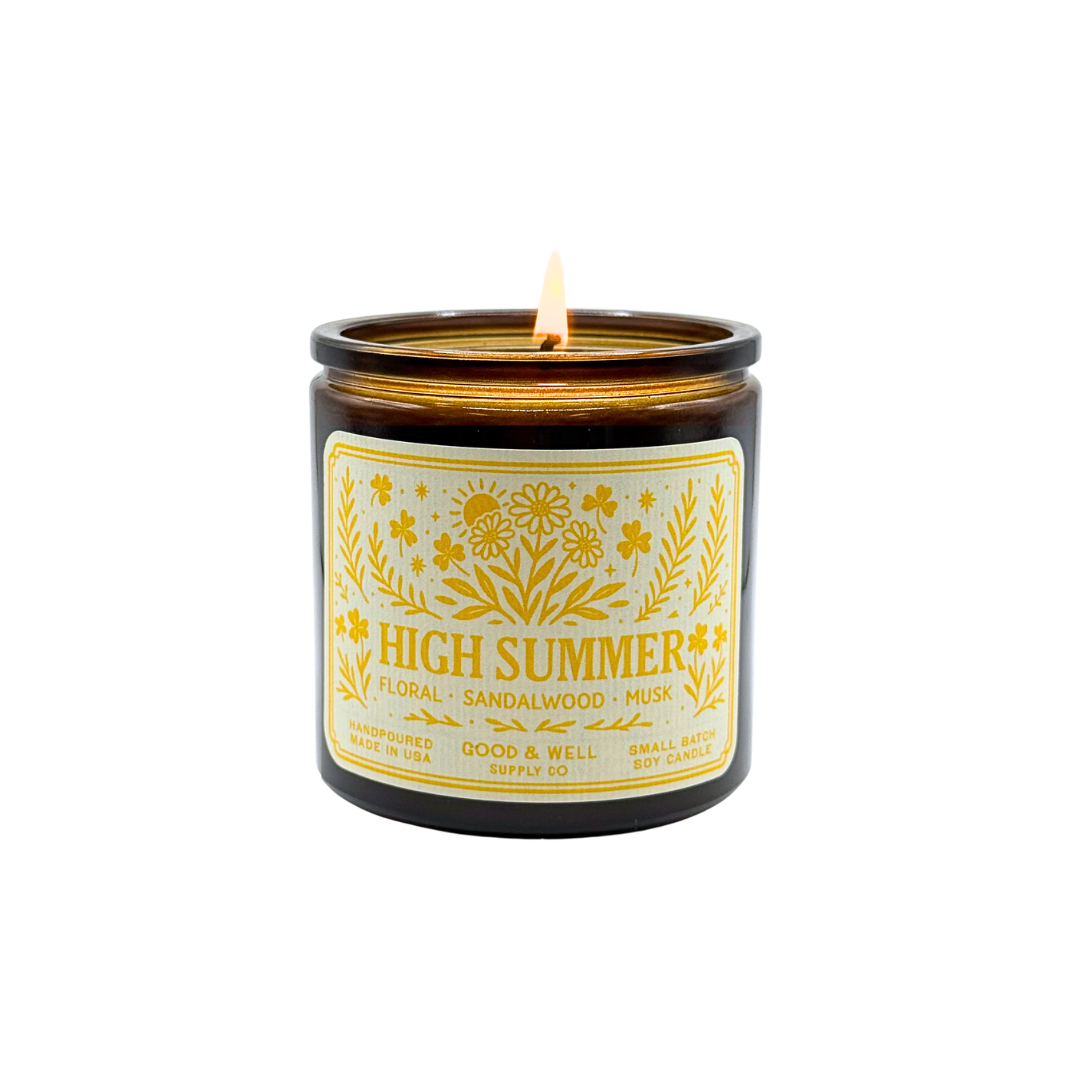 Candle labeled 'High Summer' with a lit wick on a white background