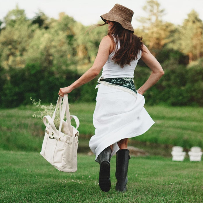 Woman running with a Coastland Supply tote outside and smiling. 