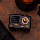 Muzen OTR Wireless FM and Bluetooth Speaker in Black on a marble table at Addison West