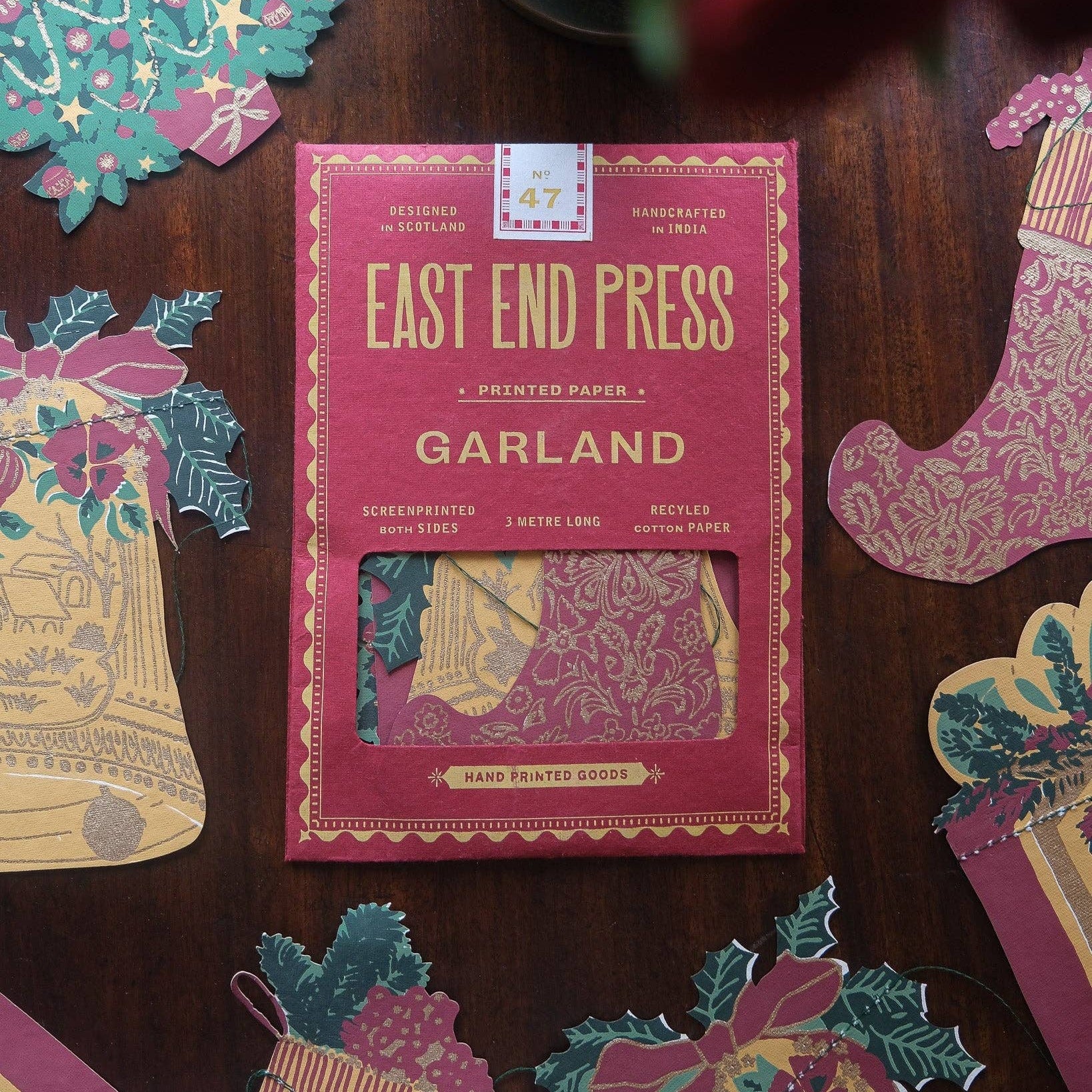East End Press Garland packaging on a wooden surface with decorative paper pieces.