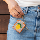Lemon Needlepoint Keychain Kit with a model at Addison West