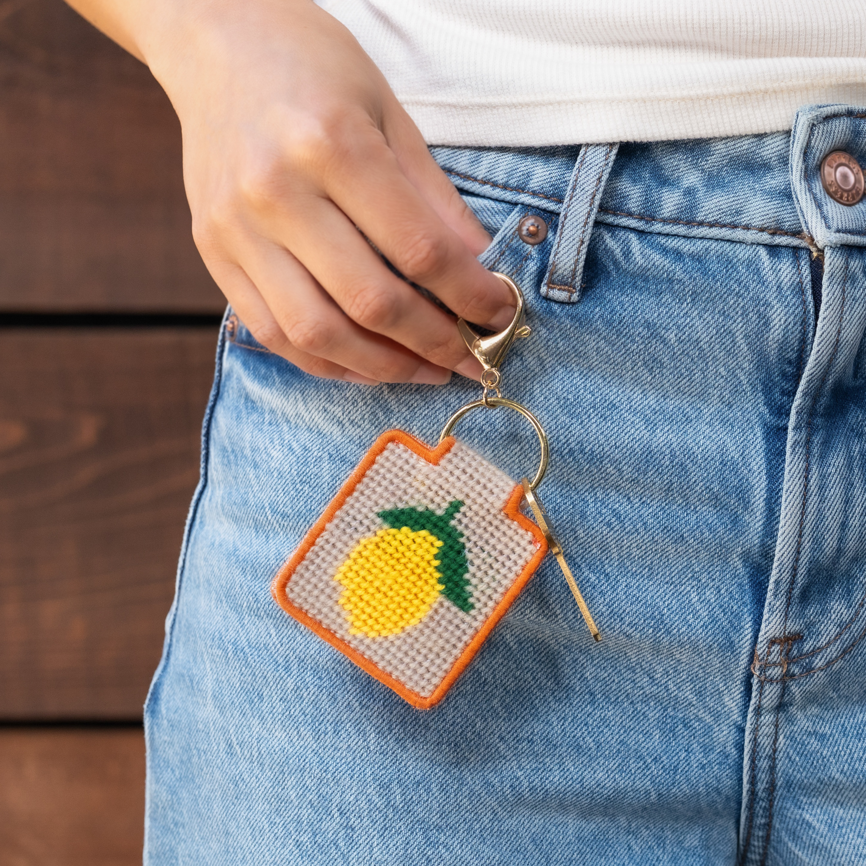 Lemon Needlepoint Keychain Kit with a model at Addison West