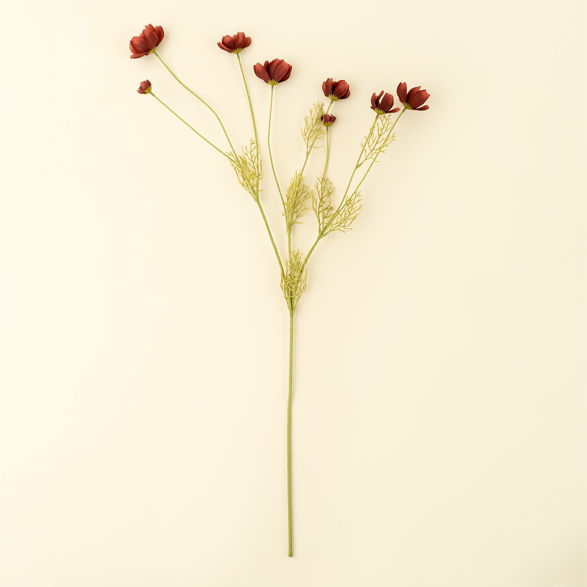 Artificial flower stem with red flowers on a beige background