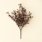 Artificial plant branch with dark red leaves on a beige background