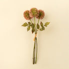 Artificial flower arrangement with pink allium flowers with green stems on a beige background