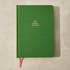 Green travel journal with 'The Travel Journal' text on a beige background