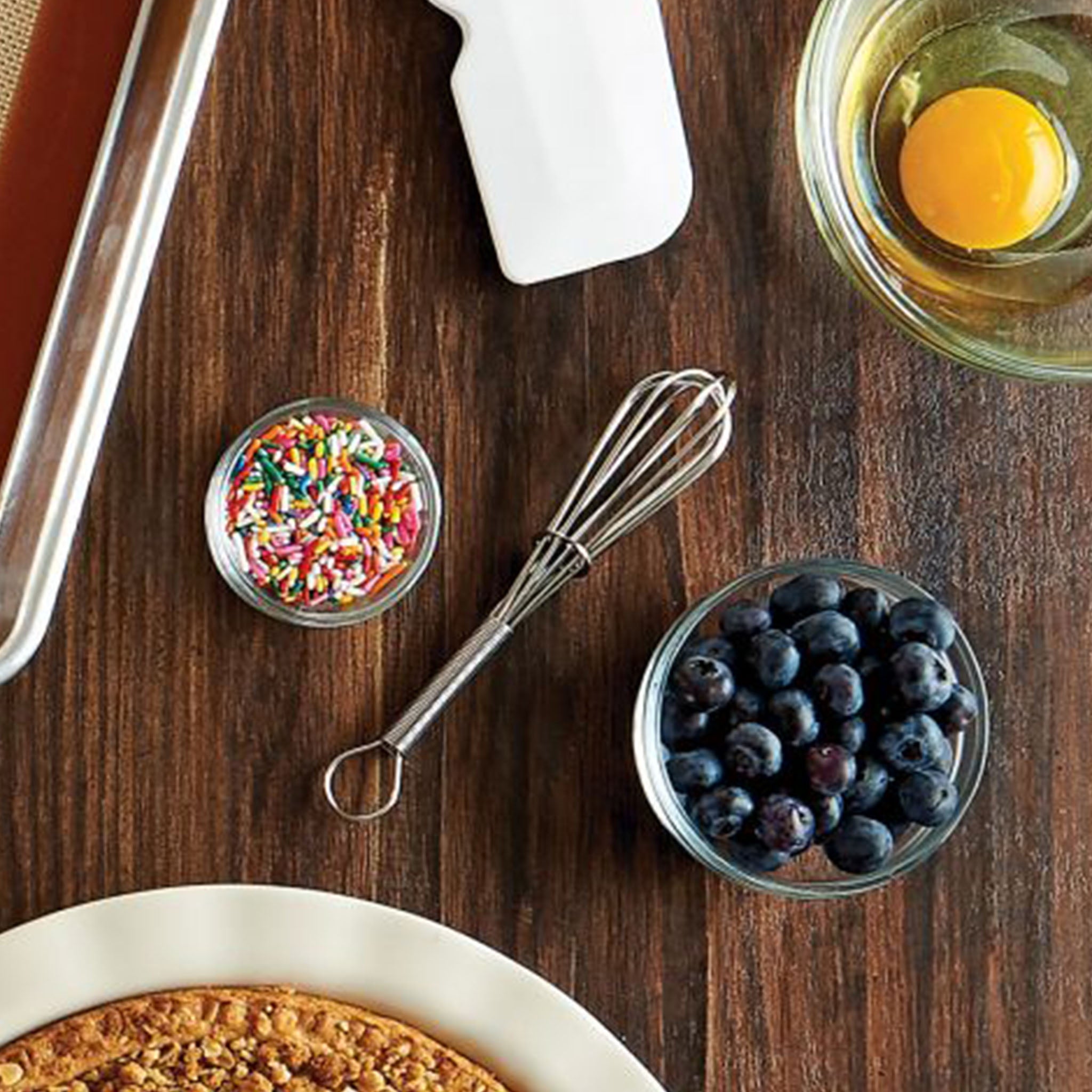 Wood counter with bowls of baking supplies and 6 inch mini whisk 