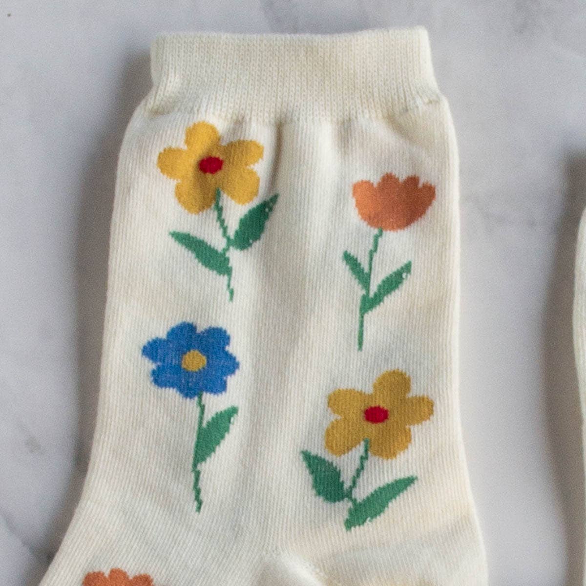 Favorite Flower Socks in Cream on a table at Addison West