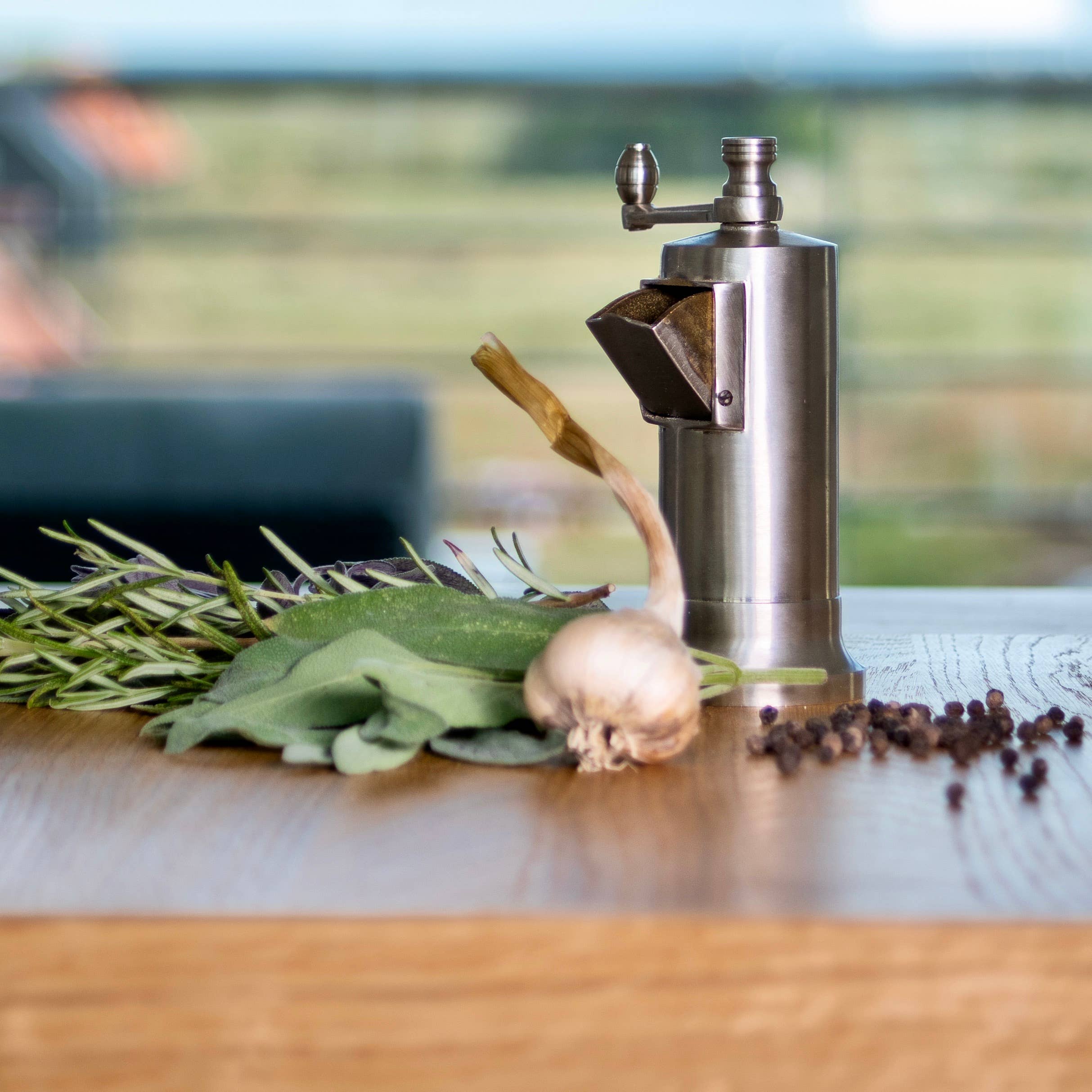 Chrome Alexander Chef's Mate Stainless steel pepper grinder with herbs and spices on a wooden surface