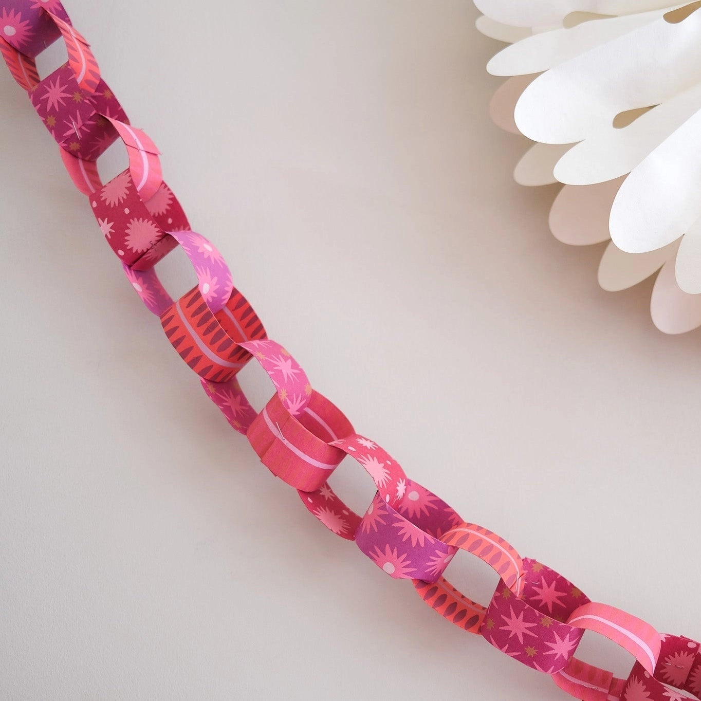 East End Press Pink & Red Paper Chain Kit on a white wall at Addison West