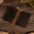 Leather Vertical Bifold Wallet in Dark Brown on a table at Addison West