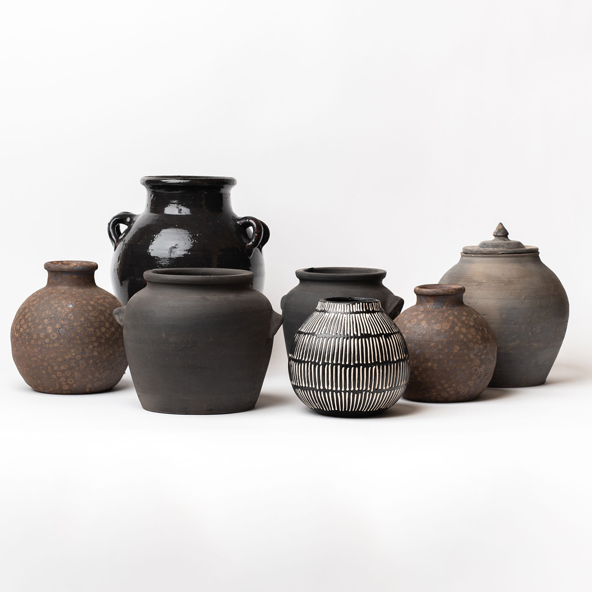 Collection of black and brown jars on a white background