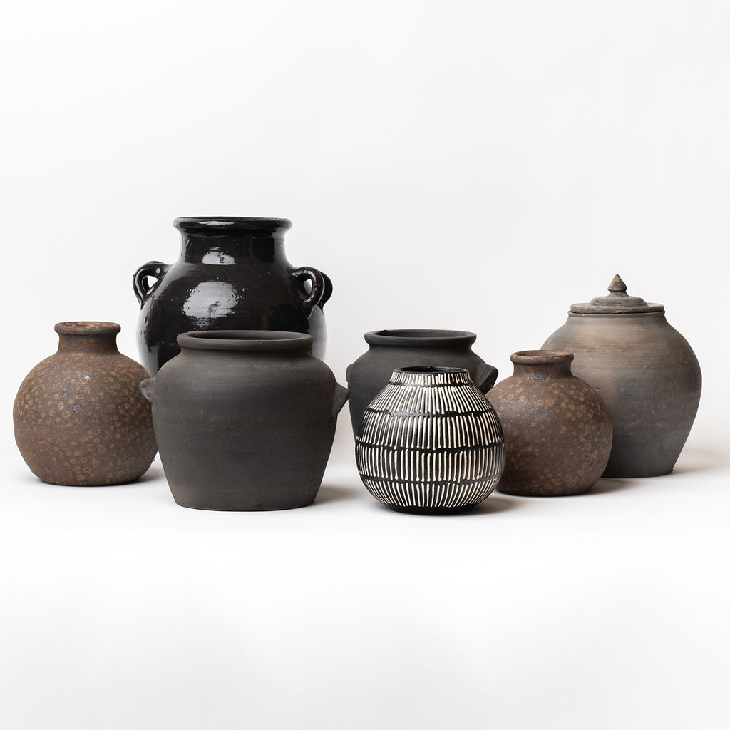 Collection of black and brown jars on a white background