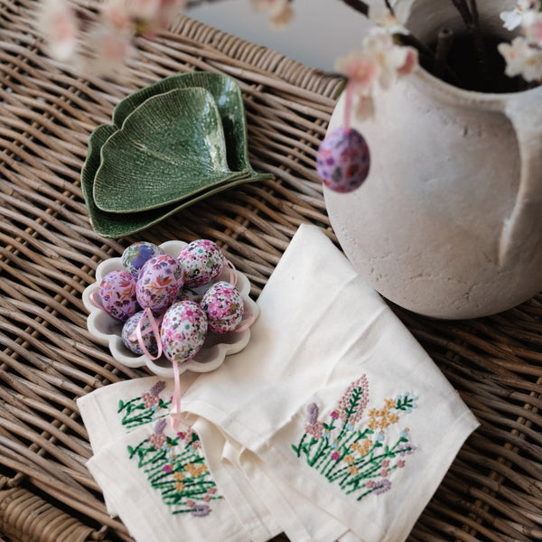 Wicker trunk with gingko plates and embroidered napkins and easter eggs