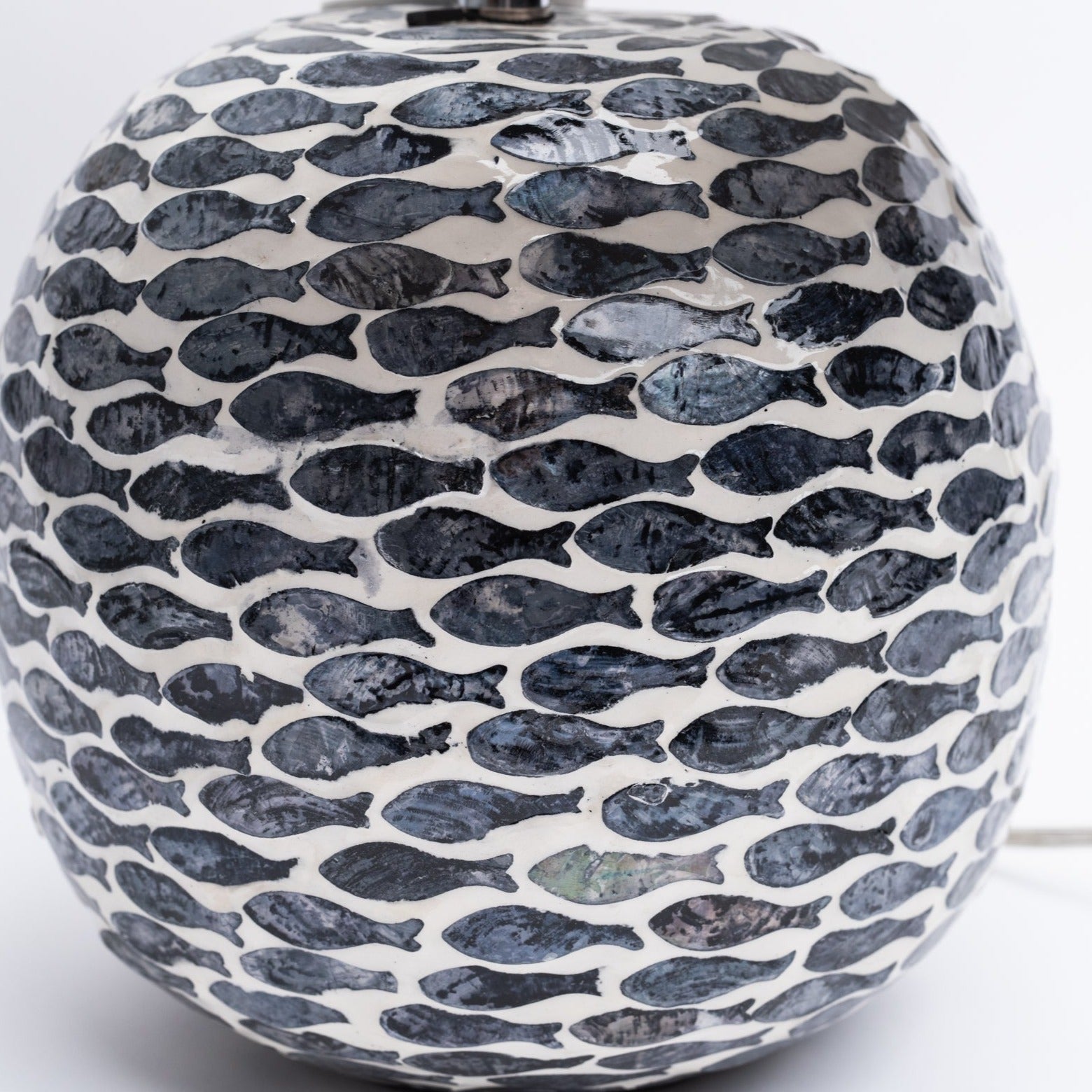 Close up of round table lamp with inlay fish pattern and linen shade on a white background from Addison West
