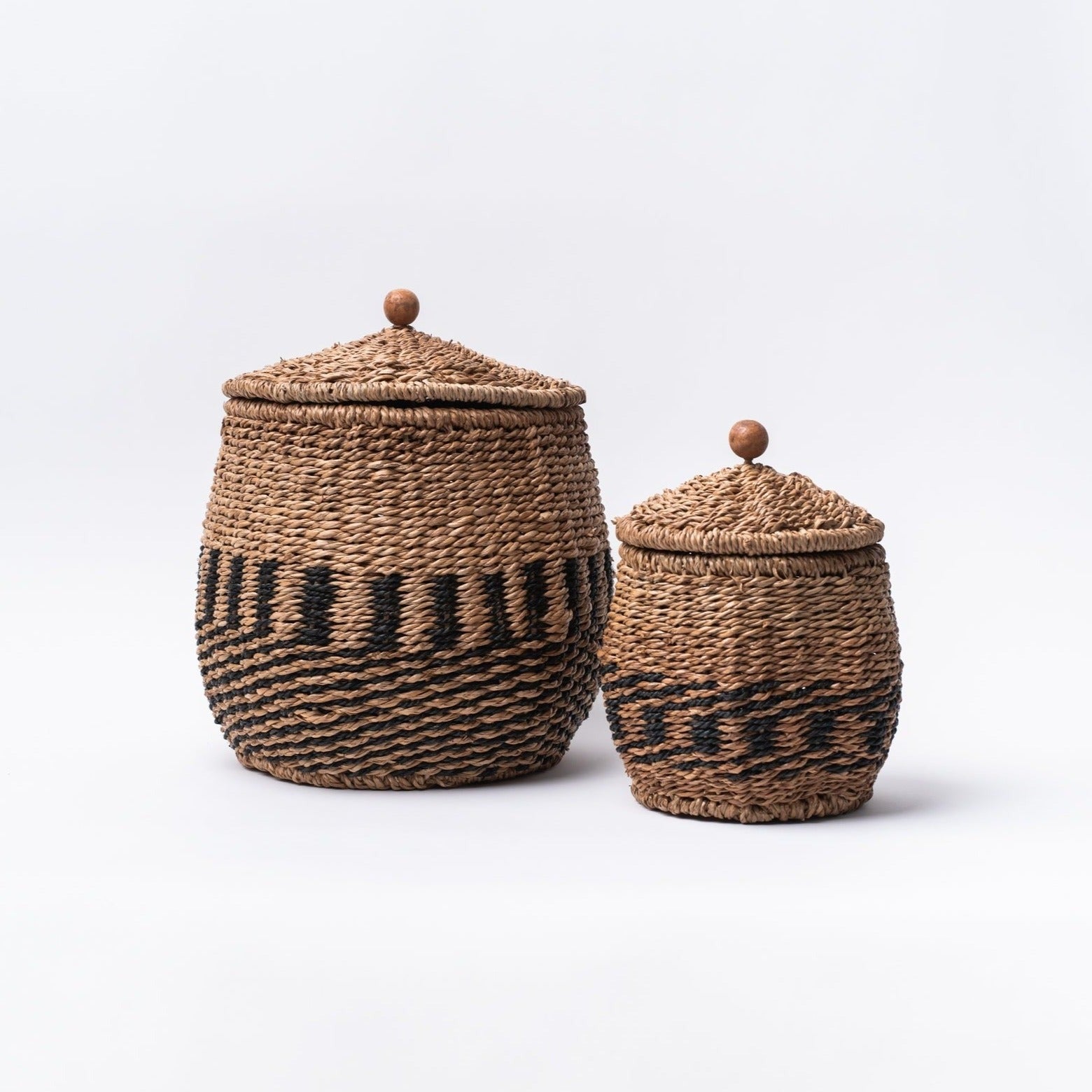 Small and large Hand-Woven black and natural Bankuan Baskets with lids with small wood knobs on a white background