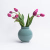 Round Blue vase with tulips in it on a white background