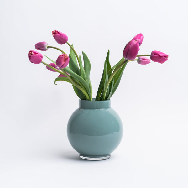 Round Blue vase with tulips in it on a white background
