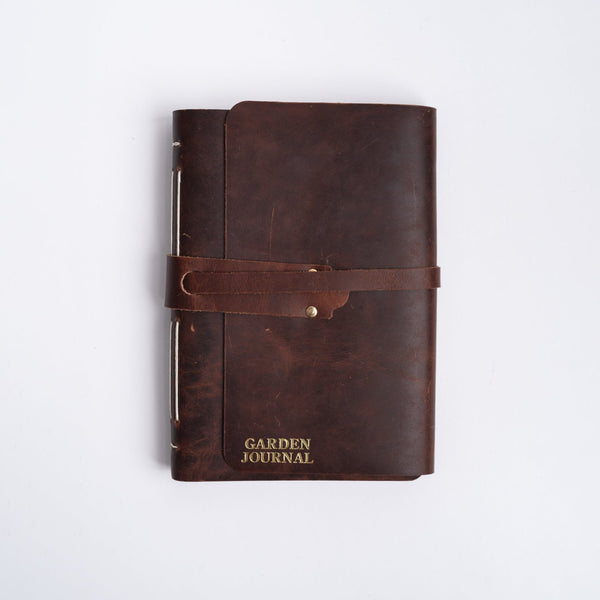 Handmade leather garden journal with strap on white background
