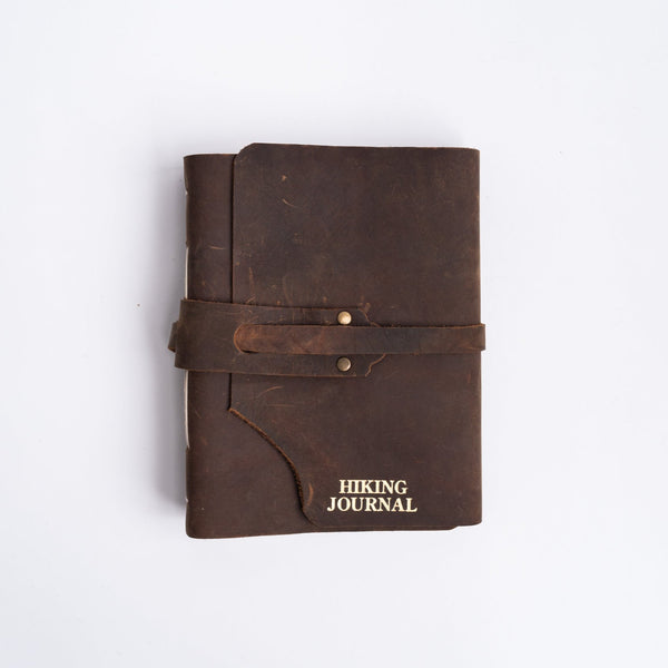 Handmade leather hiking journal with strap on white background