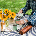 High Camp Parkside Flask in Cypress Green on a picnic blanket with a model at Addison West