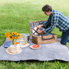 Covington Classic Willow Four Person Picnic Basket on a picnic blanket with a model at Addison West
