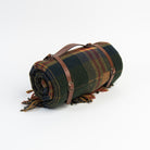 Plaid blanket with fringes and leather straps on a white background