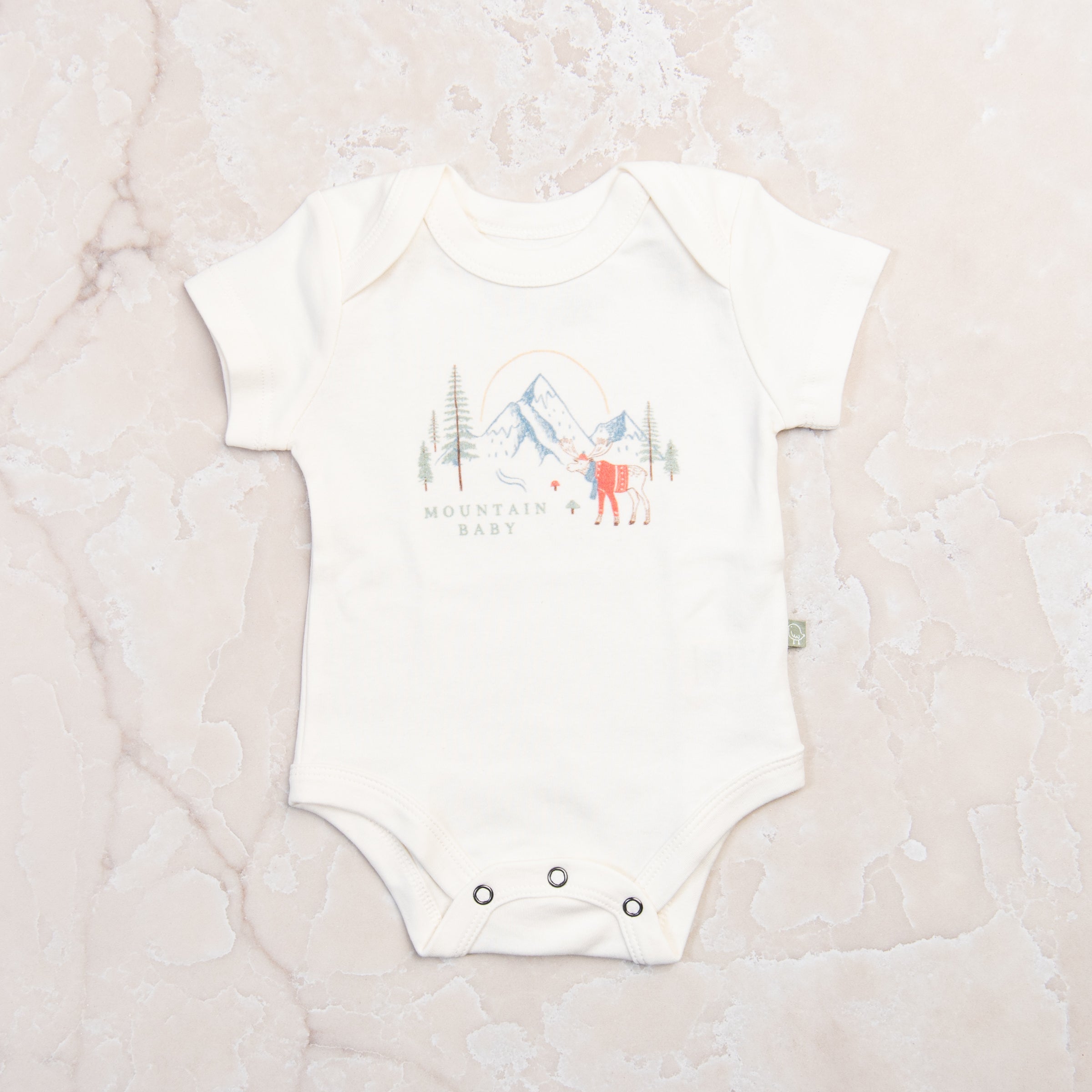 Mountain Baby Organic Cotton Babysuit on a marble table at Addison West